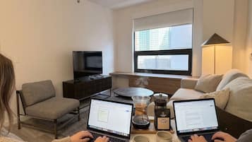 A modern living room with two laptops, a coffee maker, and a television.