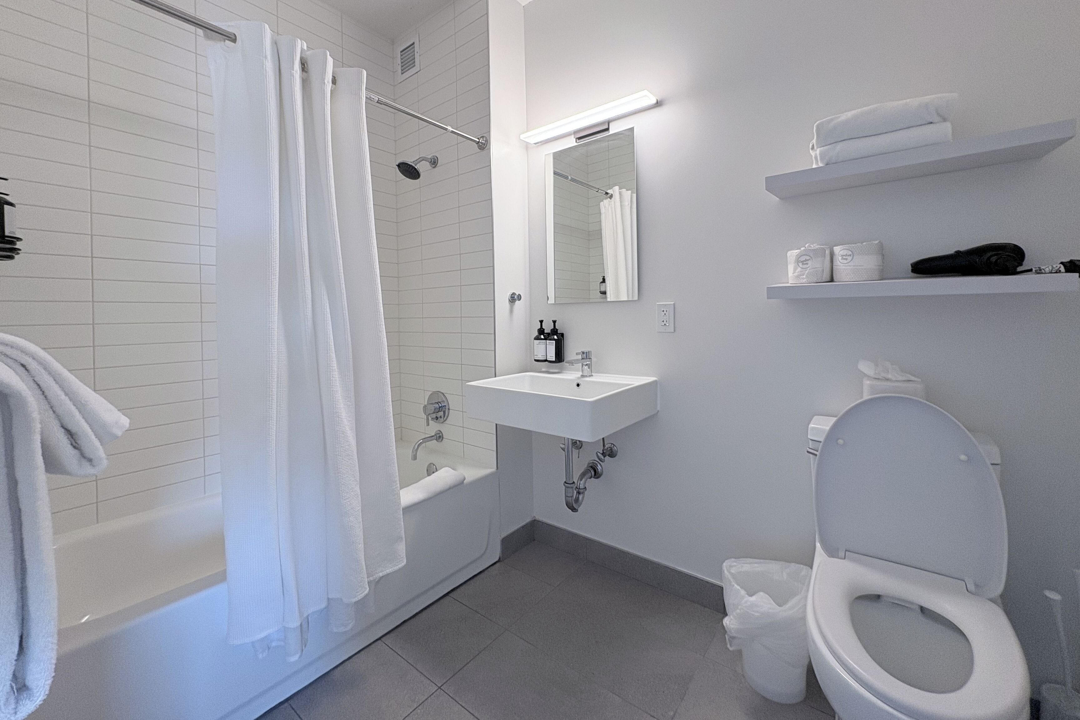 A modern bathroom with a bathtub, a sink, a toilet, and a mirror.