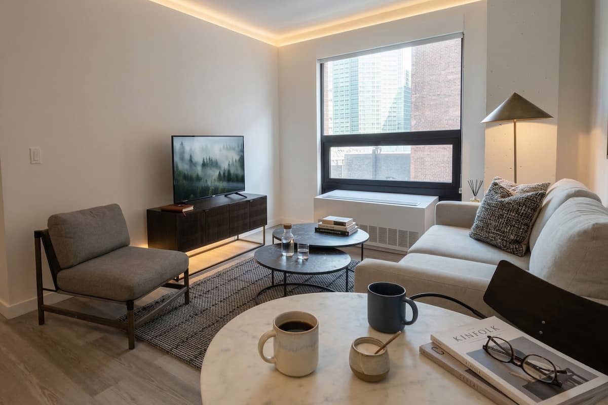 Ein modernes Wohnzimmer mit Sofa, Sessel, Couchtisch und Fernseher.