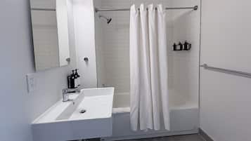 Een moderne badkamer met een witte wastafel, spiegel en douchegordijn.