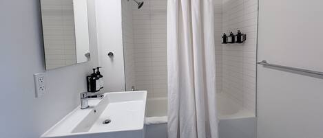 A modern bathroom with a white sink, mirror, and shower curtain.