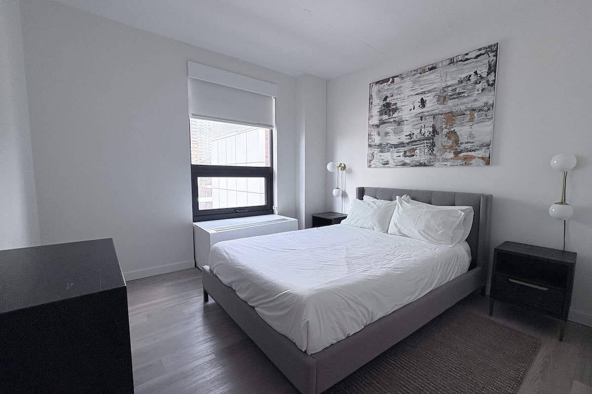 Ein modernes Schlafzimmer mit einem großen Bett, einem Fenster und einem Bild an der Wand.