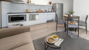A modern kitchen with white cabinets, a stainless steel range, and a dining area with a round table and chairs. - Court Square Hotel Long Island City New York , Belvilla District 6 Formerly Sonder (Long Island City)
