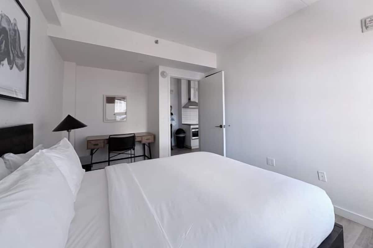 Ein Hotelzimmer mit einem großen Bett, einem Schreibtisch, einem Stuhl, einem Spiegel und einer Tür zu einem Badezimmer.