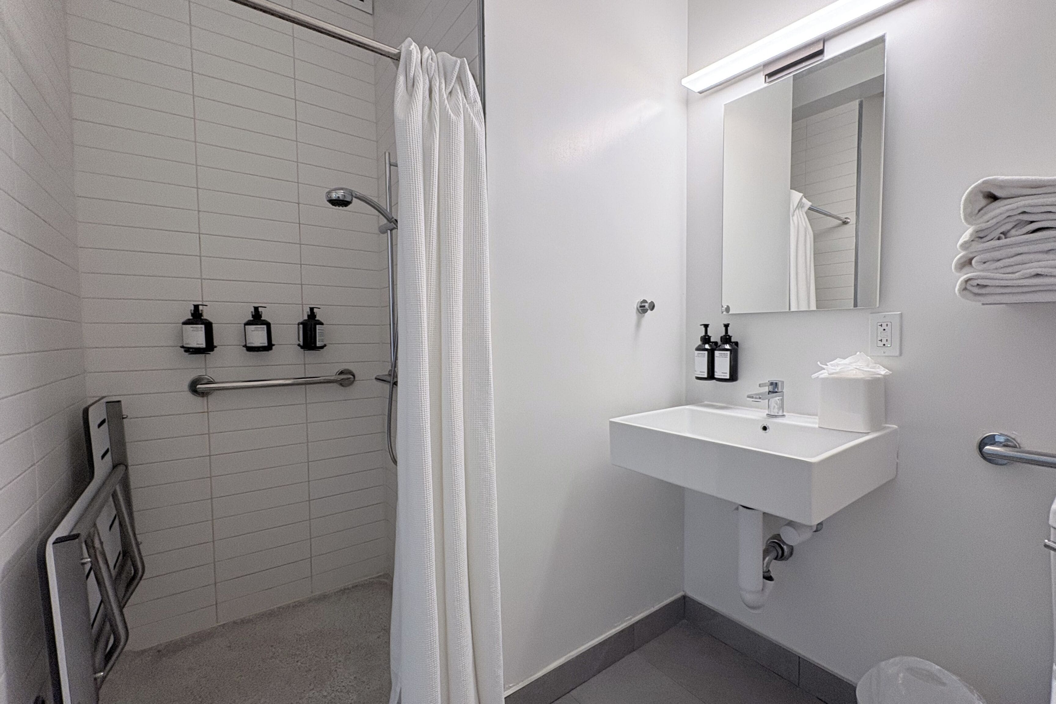 A modern bathroom with a shower, a sink, and a mirror.