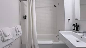 A modern bathroom with a bathtub, a shower, and a sink.