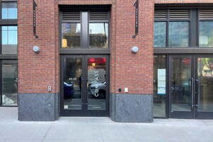 Entrada de un edificio con puerta de vidrio, un cartel que dice "Compass" y el número de la dirección visible "45-06".