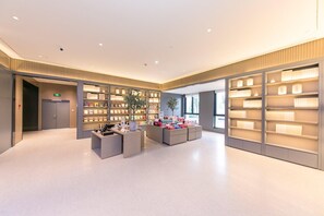 A modern interior with a reception desk, bookshelves, and a plant. - Ji Hotel (Hangzhou)