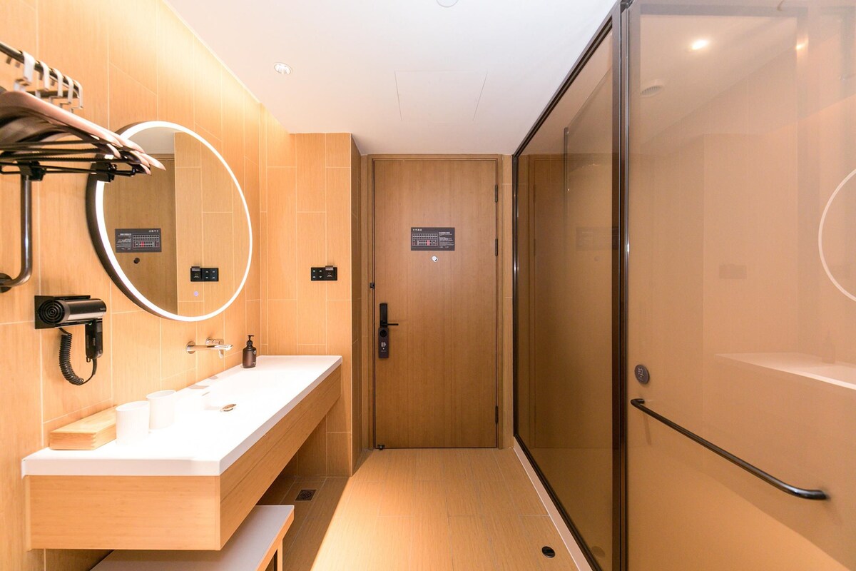 A modern bathroom with a glass shower enclosure, a sink with a mirror, and a towel rack.