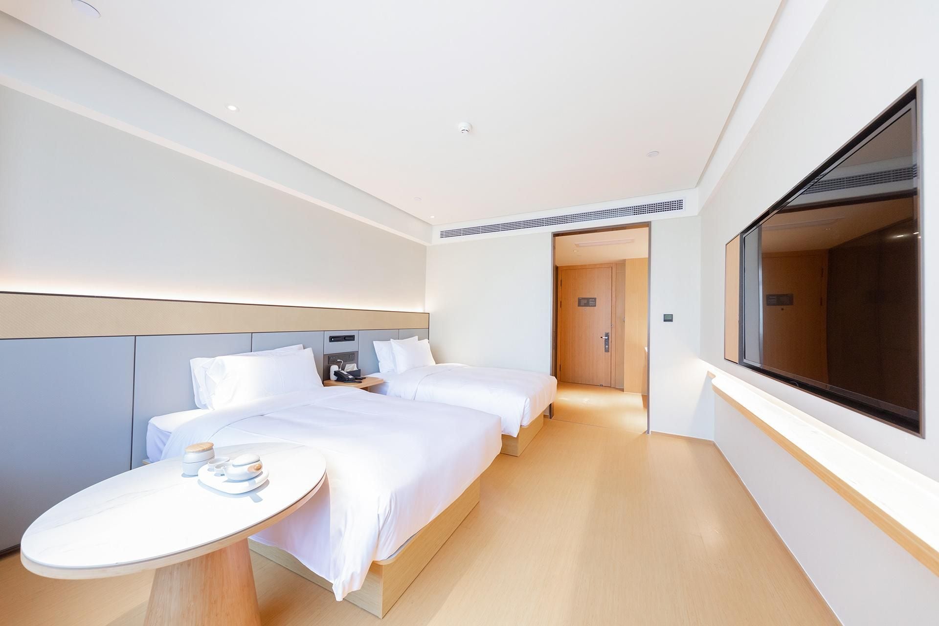 A hotel room with a bed, bedside table, and a large window.