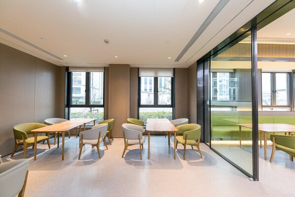 A modern meeting room with a long table and chairs, large windows, and a glass partition. - Ji Hotel (Hangzhou)