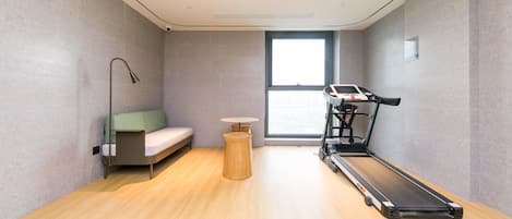 A modern room with a treadmill, a sofa, and a small table.