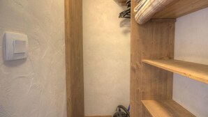 Kapea käytävä, jonka oikealla puolella on puinen hylly ja vasemmalla puolella valkoinen seinä.