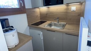 Una cucina compatta con forno a microonde, lavello e tostapane.