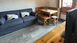 Una stanza accogliente con un divano, un tavolo in legno e una televisione.