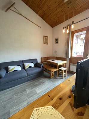 Ein gemütliches Zimmer mit einer Couch, einem Holztisch und einem Fernseher.