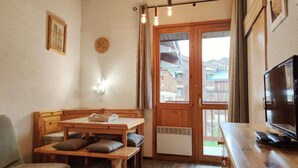 Una stanza accogliente con un tavolo di legno e panche, una televisione e una finestra vista edifici.