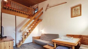 Un'accogliente stanza con una scala in legno, un divano, un tavolino e un armadietto di legno.