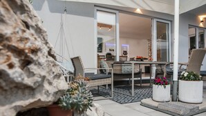 Un espace patio aménagé avec une table à manger, des chaises et des plantes en pot.