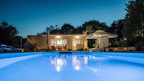 Une maison moderne dotée d’une piscine, d’un patio couvert et d’un intérieur bien éclairé.