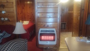 Een knus ingerichte kamer met een geruit bankje, een rood vloerkleed, een tafel met lamp en een verwarming.