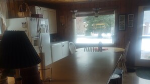 Een keuken met een groot eiland, witte kastjes en een koelkast.