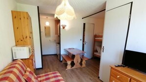 Una habitación con cama, cómoda de madera y mesa con bancos.