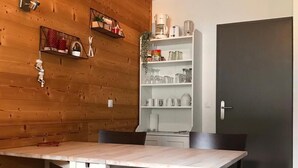 Une cuisine moderne avec un lambris en bois, un îlot central et des étagères intégrées où sont rangés les ustensiles de cuisine.
