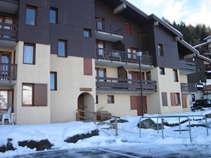 A multi-story building with balconies and a snow-covered ground.