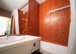 A bathroom with a wooden wall, a white sink, and a bathtub. - 200m from ski slopes, 1st floor, view ski slopes, balcony, tv, ski locker, 27m², Valmorel (Valmorel)