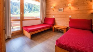 A cozy room with two beds, a bench, and a window with curtains. - 200m from ski slopes, 1st floor, view ski slopes, balcony, tv, ski locker, 27m², Valmorel (Valmorel)