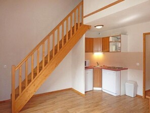 A kitchen with wooden cabinets, a white refrigerator, and a wooden staircase.