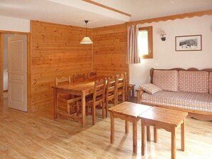 Ein Holzinterieur mit einem Esstisch, Stühlen, einer Couch und einer Lampe.