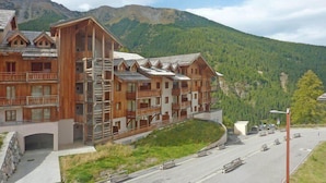Un edificio de madera de varios pisos con balcones, con montañas al fondo.