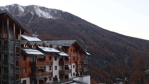 Un edificio de estilo chalet de madera con varios balcones, con montañas al fondo.