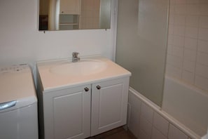 Un baño con un lavamanos blanco, un espejo encima y una zona de ducha.
