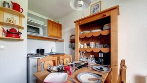 Una cucina compatta con mobili in legno, un forno a microonde e un tavolo da pranzo per quattro persone.