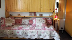 Et hyggeligt rum med en træskab, en quiltet sofa og et sengebord med en lampe.