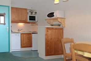 Kitchen features a dishwasher, microwave, and oven, with a chair and table nearby.