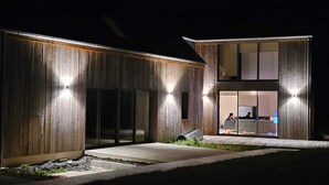 A modern building with a wooden facade and large glass doors leading to an interior space.