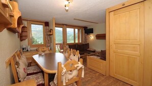Ein gemütliches Zimmer mit einem Holzesstisch, Stühlen, einer Couch und einem Fernseher.