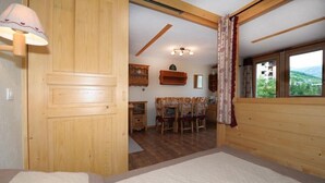 Ein Schlafzimmer mit Bett, Holzwänden, einem Fenster mit Blick, einem Schreibtisch mit Stühlen und einer Lampe.