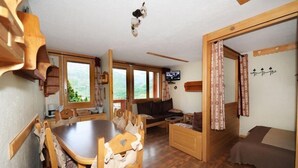 Ein gemütliches Zimmer mit Holztisch, Stühlen, einer Couch und einem Bett.