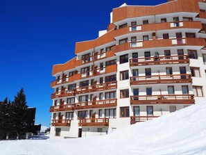 A multi-story hotel with balconies and a snowy background. - 250m from resort center, 6th floor, view mountain, tv, 21m², Les Menuires (Les Menuires)