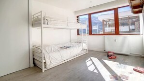 Une chambre avec des lits superposés offrant une vue sur les montagnes grâce à de grandes fenêtres.