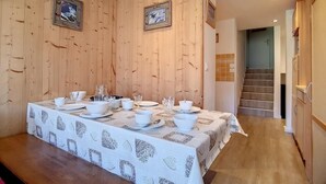 Ein Essbereich mit einem langen Tisch, der für eine Mahlzeit gedeckt ist, Holzwänden und gerahmten Bildern an der Wand.