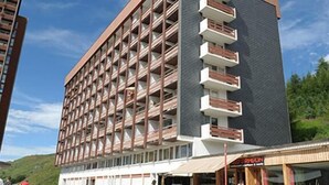 Ein mehrstöckiges Hotel im modernen Stil, mit Balkonen an jeder Etage und einer flachen Dachfläche.