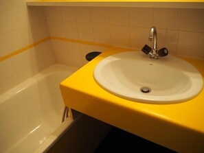 Un baño con bañera, lavamanos y encimera amarilla.