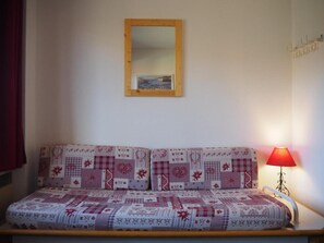 Una habitación con una cama, una lámpara roja y un espejo en la pared.