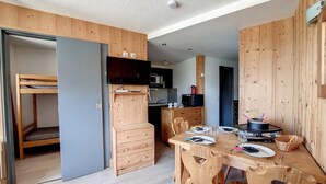 A compact room with a bunk bed, a kitchenette, a dining table with chairs, and a television. - 2nd floor, balcony, tv, ski locker, 24m², Les Menuires (Les Menuires)